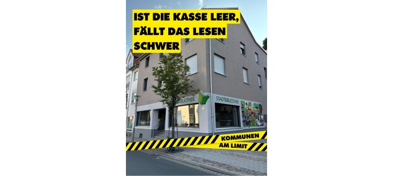 Gebäude einer Stadtbibliothek mit Kampagnenbotschaft „Ist die Kasse leer, fällt das Lesen schwer“, die auf die Bedeutung kommunaler Finanzierung für Bildung und Kultur aufmerksam macht.