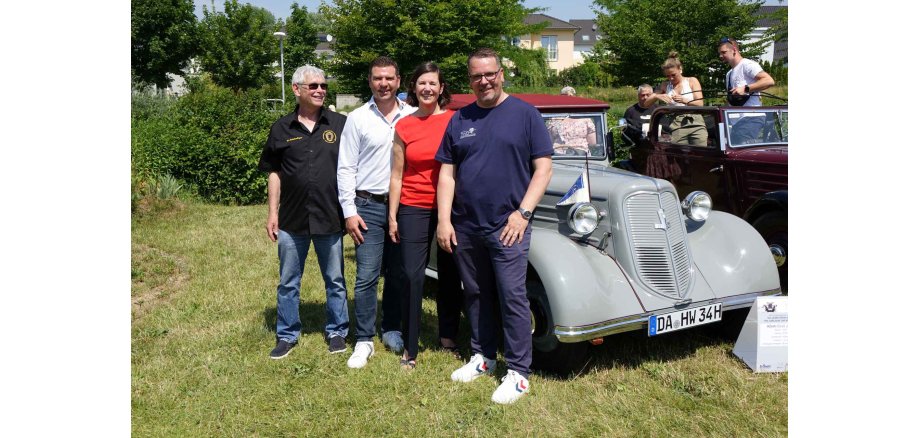 Werner Schollenberger, Bürgermeister Tobias Silbereis, Kreisbeigeordnete Christel Spößler und Ingo Köhler vom Hessischen Wirtschaftsarchiv. Gruppenfoto von Gästen und Organisatoren bei einer Jubiläumsveranstaltung mit historischem Fahrzeug im Freien.