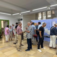 Menschen betrachten historische Infotafeln und Exponate in einer Ausstellung.
