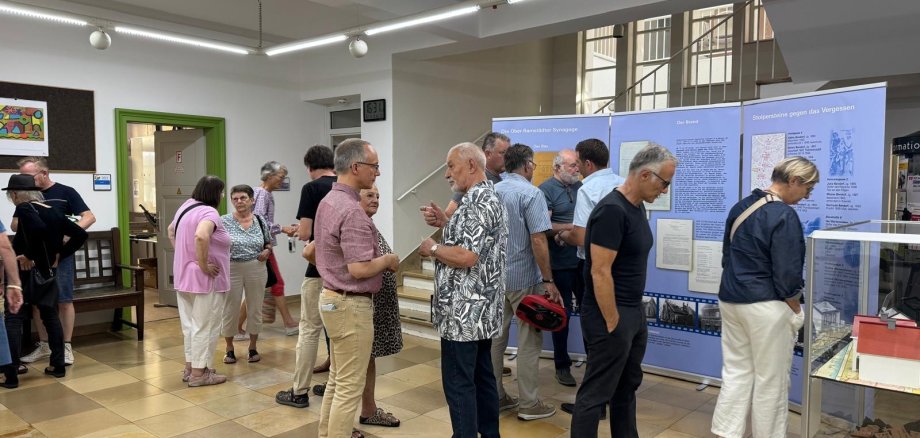 Menschen betrachten historische Infotafeln und Exponate in einer Ausstellung.