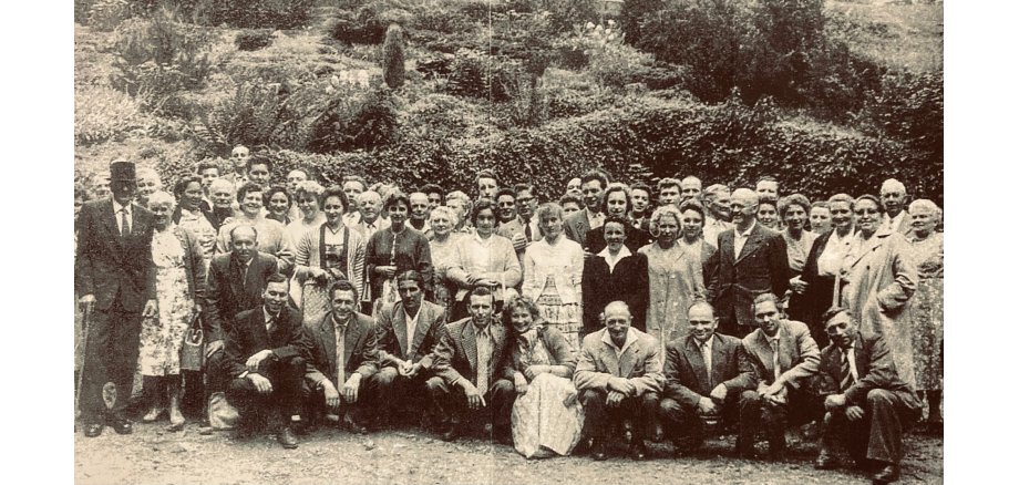 Die Siedler auf dem Eiche in den 50er Jahren. Historische Schwarz-Weiß-Gruppenaufnahme aus den 1950er-Jahren mit zahlreichen Frauen und Männern unterschiedlichen Alters. Die Personen stehen und knien in mehreren Reihen im Freien vor einer dicht bewachsenen Böschung