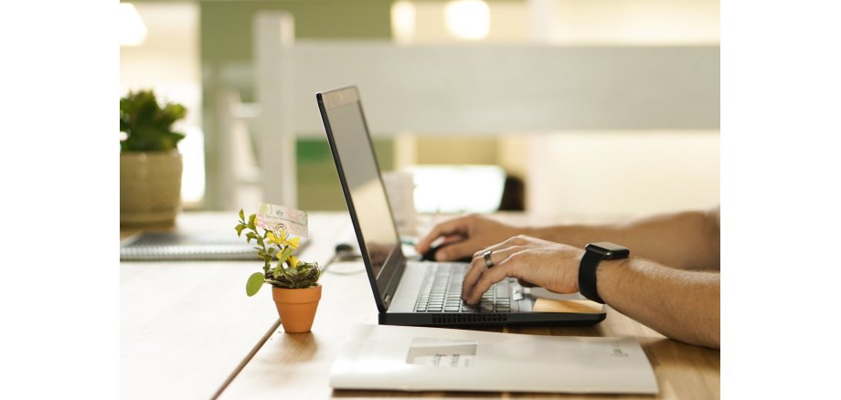 Person arbeitet an einem Laptop in einer modernen Büroumgebung und nutzt digitale Werkzeuge für Kommunikation und Organisation.
