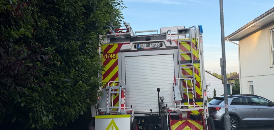 Feuerwehrauto im Einsatz Ein Feuerwehrfahrzeug steht rückwärts in einer engen Wohnstraße, dicht zwischen einer Hecke und einer Straßenlaterne.