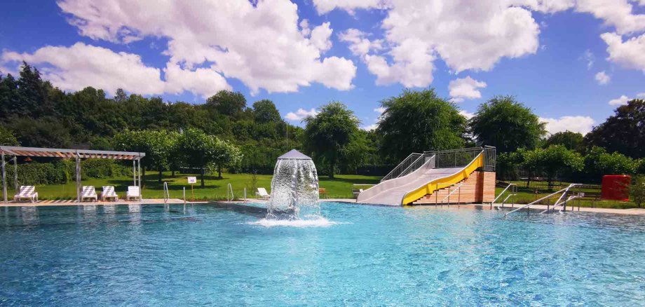 Das Freibad in Ober-Ramstadt Das Bild zeigt das Freibad mit einer Rutsche, grüne Wiese und Sonnenliegen