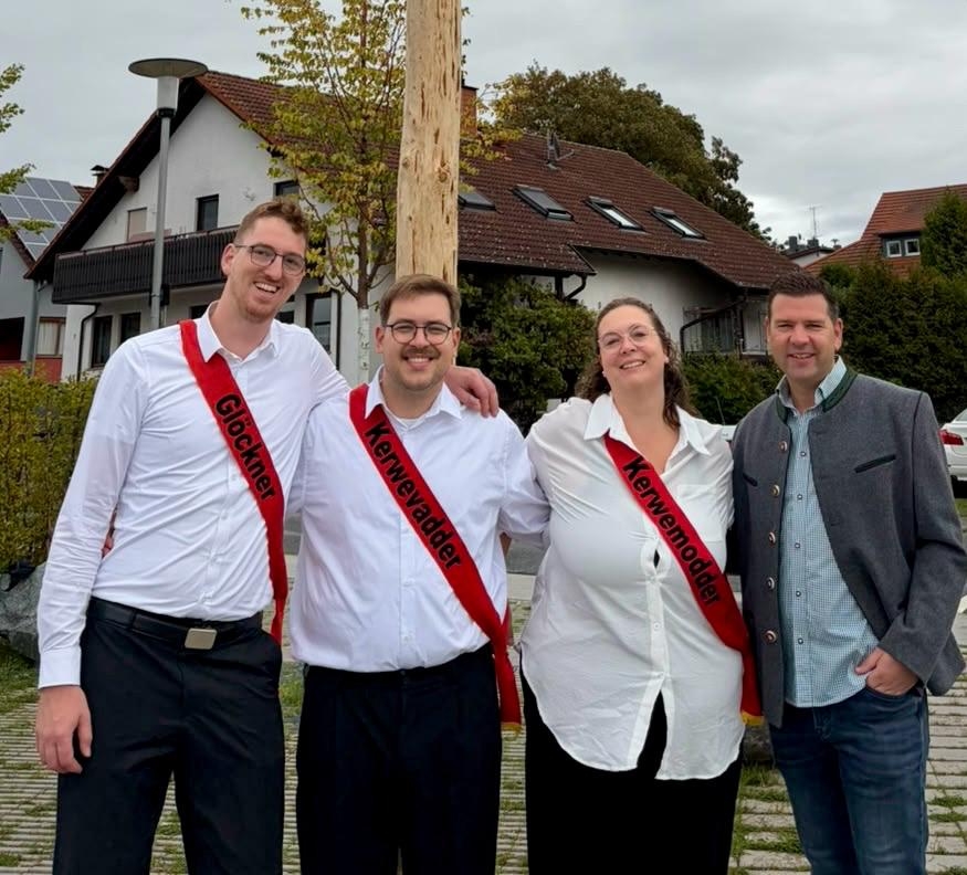 Vier Personen stehen lächelnd nebeneinander im Freien. Drei von ihnen tragen rote Schärpen mit den Aufschriften ‚Glöckner‘, ‚Kerwevadder‘ und ‚Kerwemodder‘.