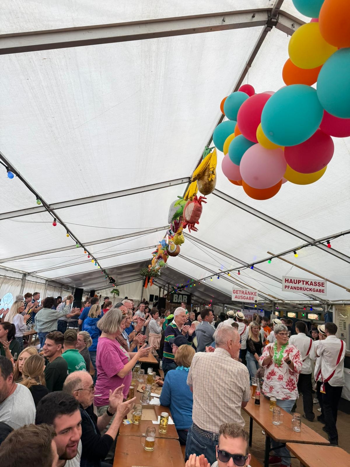 Die Stimmung im Festzelt am Kerbsonntag ist bestens. Viele Menschen sitzen und stehen an langen Holzbänken in einem Festzelt mit bunten Luftballons und genießen das Kerb-Programm.