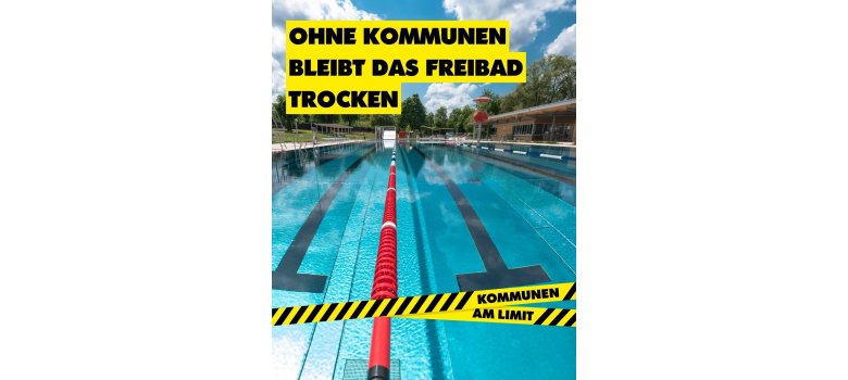 Schwimmbecken eines Freibads mit Kampagnenbotschaft „Ohne Kommunen bleibt das Freibad trocken“, die auf die Bedeutung kommunaler Finanzierung und Infrastruktur hinweist.