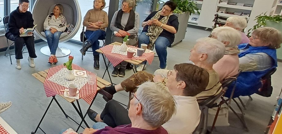Lese-Kränzchen in der Stadtbibliothek in Ober-Ramstadt Eine Gruppe sitzt in einem Kreis in einer Bibliothek und hört einer Person beim Vorlesen zu