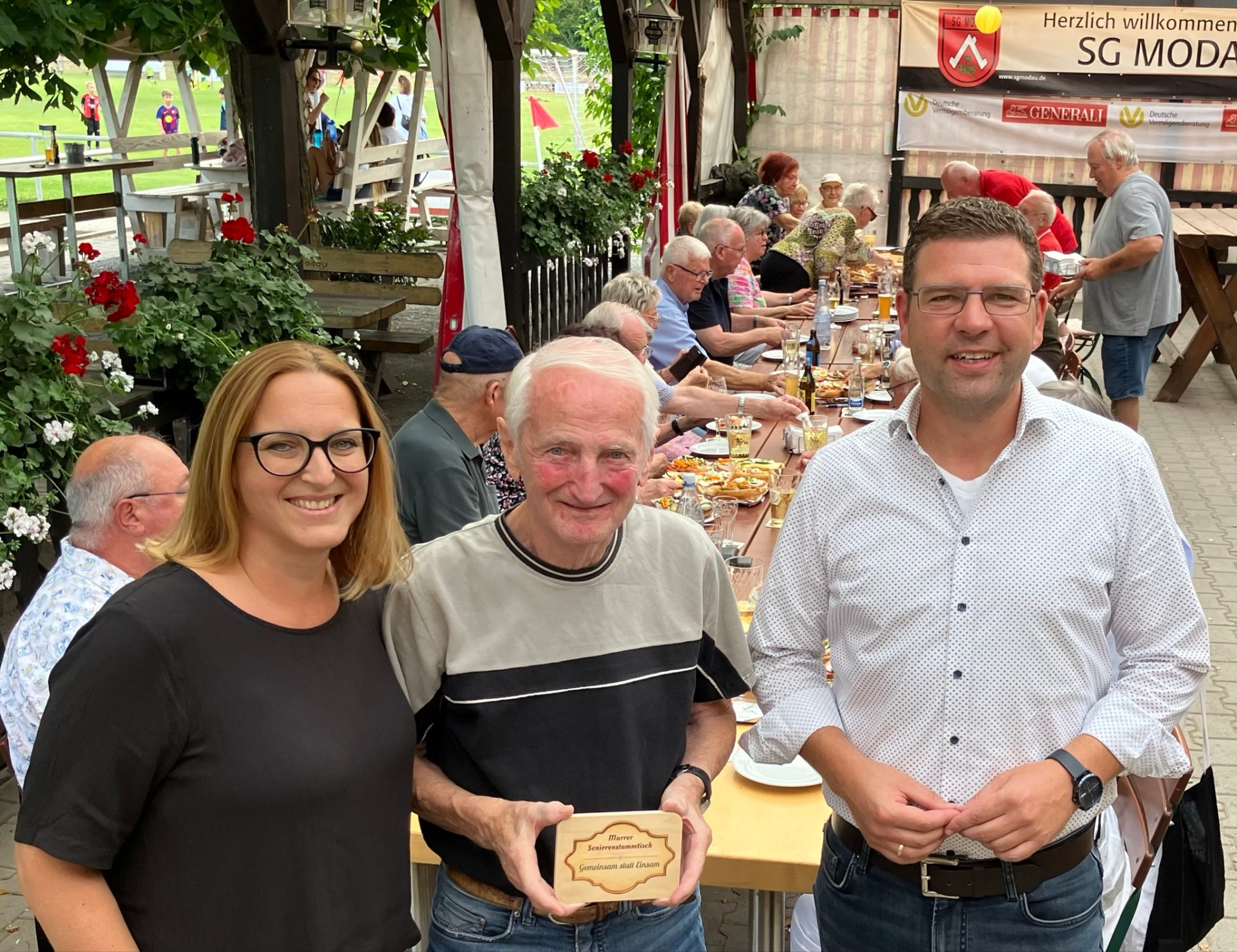 Seniorinnen und Senioren sitzen im Sportheim der SG Modau in gemütlicher Runde beisammen. Auf dem Tisch stehen belegte Brötchen und Getränke.