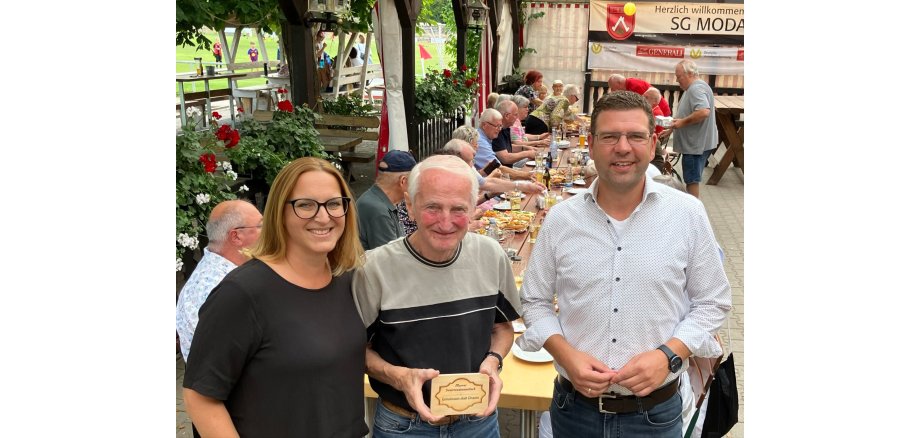 Seniorinnen und Senioren sitzen im Sportheim der SG Modau in gemütlicher Runde beisammen. Auf dem Tisch stehen belegte Brötchen und Getränke.