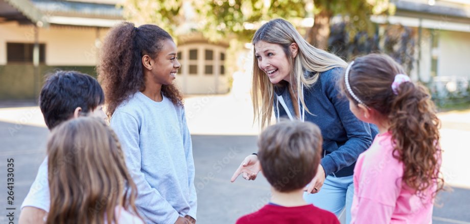 Eine Gruppe fröhlicher Kinder mit ihrer Betreuerin.